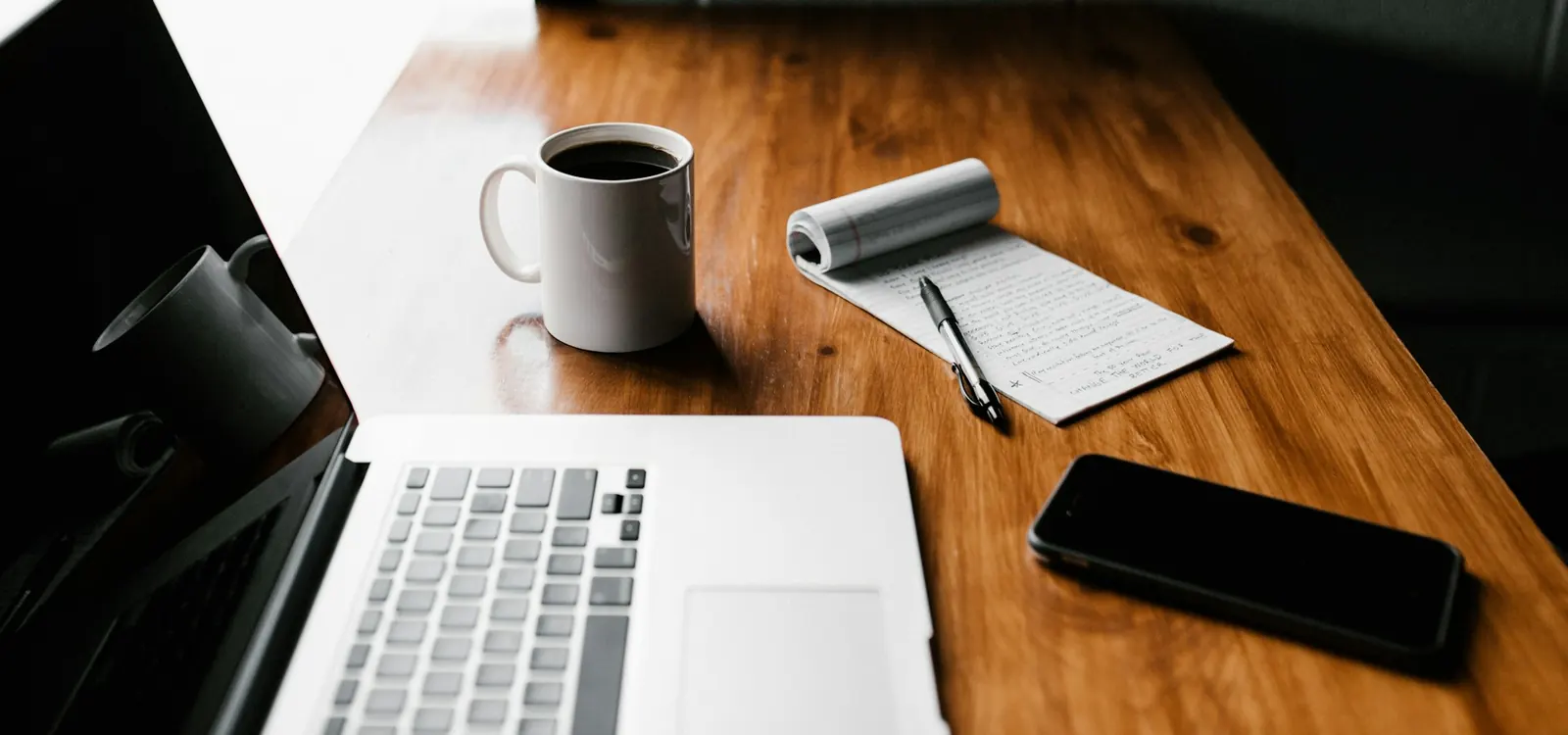 Laptop, coffee mug and phone on a desk